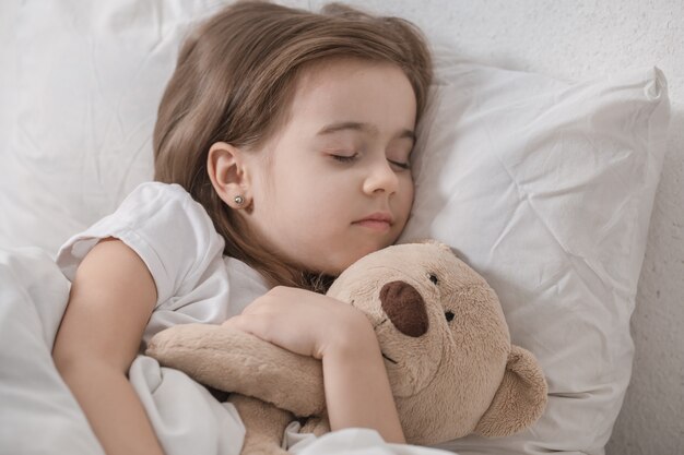 Śliczna mała dziewczynka w łóżku z pluszową zabawką