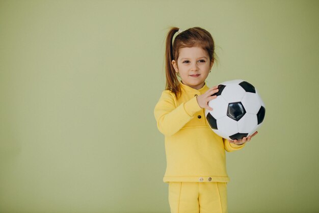Śliczna mała dziewczynka z piłką nożną w studio