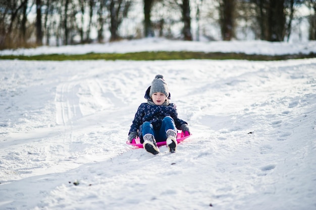Bezpłatne zdjęcie Śliczna mała dziewczynka ze spodkami na saniach na zewnątrz w zimowy dzień