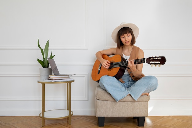 Śliczna młoda kobieta gra na gitarze w pomieszczeniu