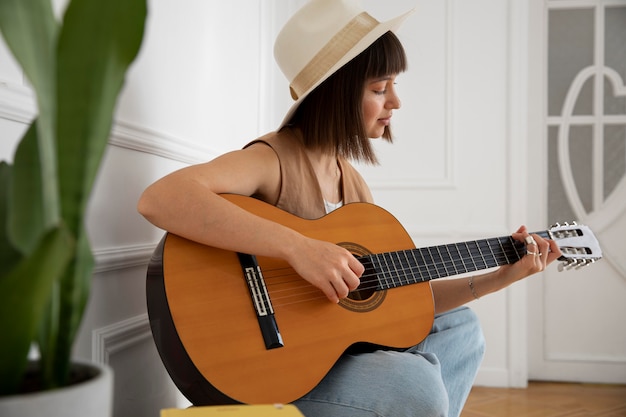 Śliczna młoda kobieta gra na gitarze w pomieszczeniu