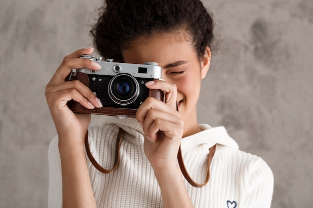 Śliczna modniś kobieta bierze fotografie na retro kamerze