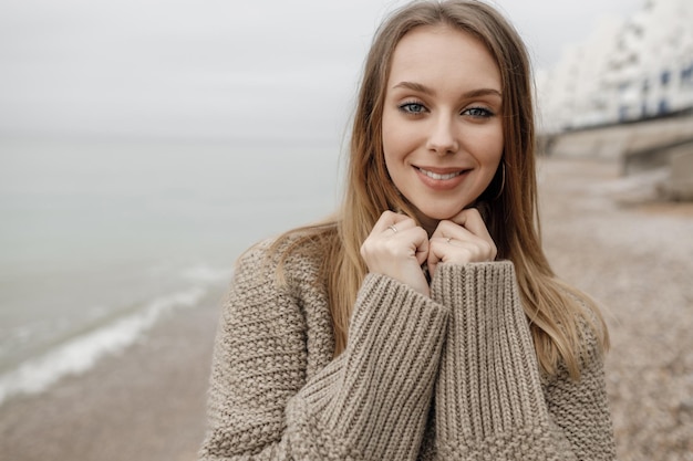 Bezpłatne zdjęcie Śliczna przytulna uśmiechnięta kobieta na zewnątrz blisko morza