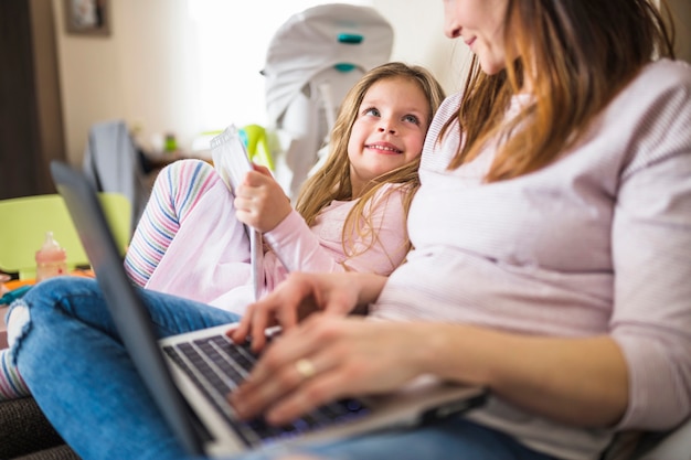 Śliczna Uśmiechnięta Dziewczyna Patrzeje Jej Macierzystego Używa Laptop