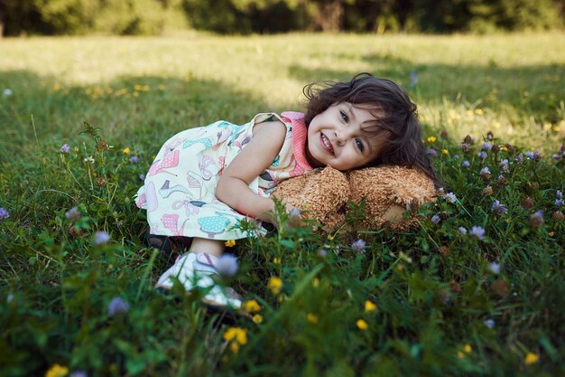 Śliczna uśmiechnięta dziewczynka ściska miękkiego niedźwiedzia zabawkę