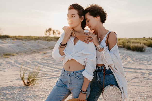 Śliczne dwie młode kobiety bawiące się na plaży o zachodzie słońca, gejowska lesbijka kochają romans