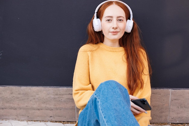 Bezpłatne zdjęcie Śliczne rude włosy młoda kobieta w słuchawkach na zewnątrz