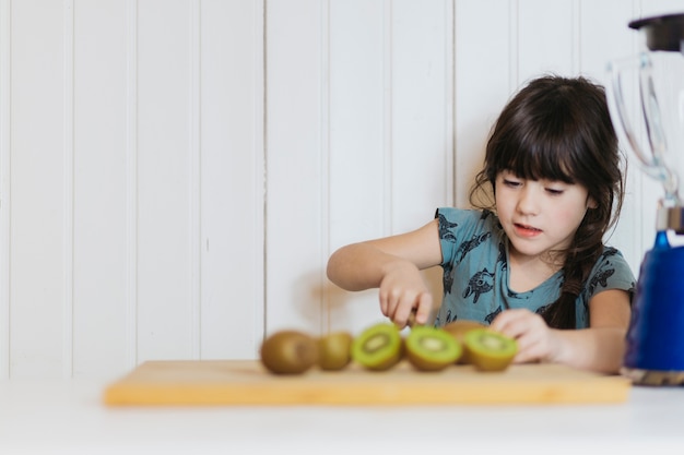 Ślicznej małej dziewczynki tnący kiwifruit