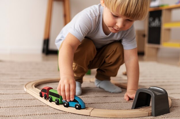 Śliczny dzieciak bawiący się drewnianym pociągiem w pełnym ujęciu