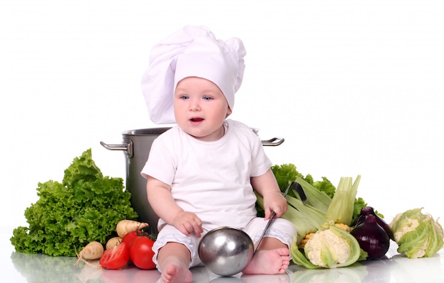 Śliczny dziecko szef kuchni z dużym garnkiem i warzywami