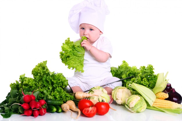 Śliczny dziecko szef kuchni z różnymi warzywami