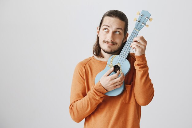 Śliczny hipster stroi struny, grając na ukulele