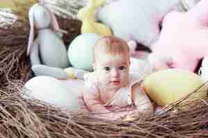 Bezpłatne zdjęcie Śliczny mały dziecko z kolorowymi wielkanocnymi jajkami i zabawkarskim królika lying on the beach w gniazdeczku.