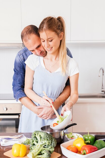 Śliczny młody człowiek kocha jego żony przygotowywa jedzenie w kuchni