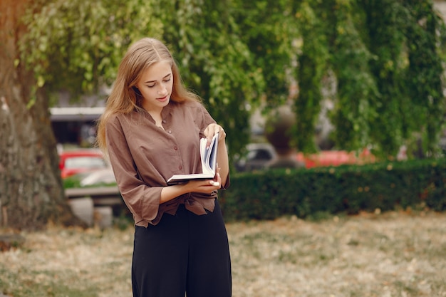 Śliczny uczeń pracuje w parku i używa notatnika