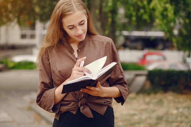 Śliczny uczeń pracuje w parku i używa notatnika