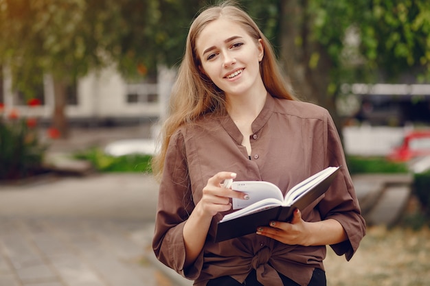 Śliczny uczeń pracuje w parku i używa notatnika