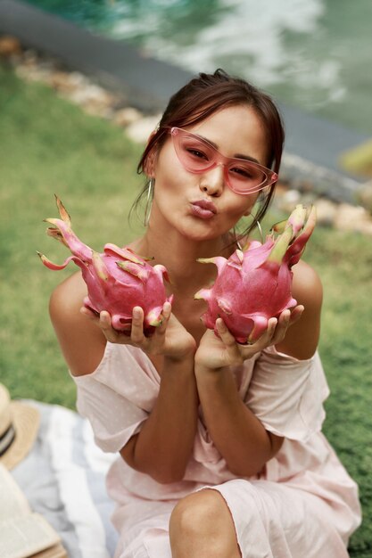 Słodkie azjatyckie kobiety trzymającej w rękach różowe smocze owoce