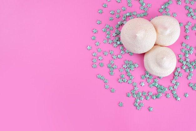 Słodkie bezy z widokiem z góry i cukierki w kształcie gwiazdy na różowym biurku, słodki cukier-cukier kolor