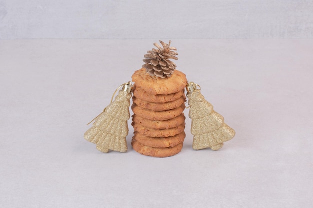 Bezpłatne zdjęcie słodkie ciasteczka ze złotymi świątecznymi zabawkami na białym stole.