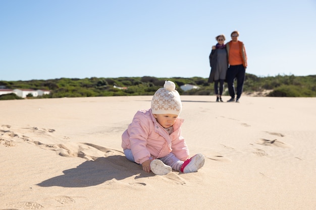 Słodkie dziecko na sobie różową kurtkę i kapelusz, bawiąc się na piasku na świeżym powietrzu