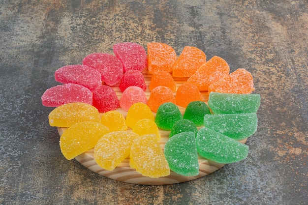 Bezpłatne zdjęcie słodkie kolorowe galaretki cukierki na drewnianym talerzu