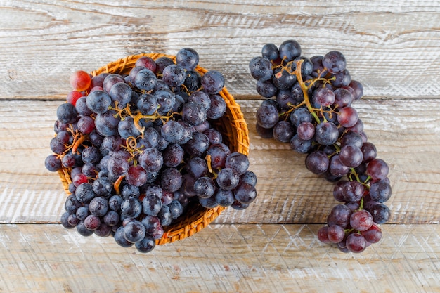 Bezpłatne zdjęcie słodkie winogrona w wiklinowym koszu na drewnianym tle. leżał płasko.