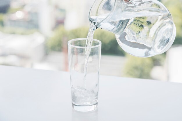 Słoik napełnia szklankę wody