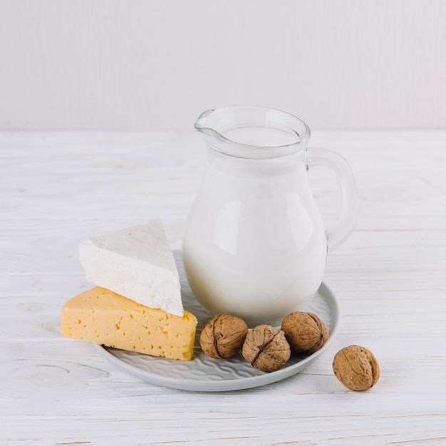 Słój mleka; ser i orzechy włoscy na białym drewnianym stole