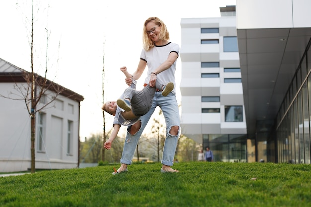 Bezpłatne zdjęcie słońce świeci za szczęśliwym synem i mamą bawiąc się podczas zabawy na dworze