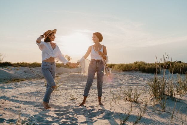 Słoneczne szczęśliwe dwie młode kobiety bawiące się na plaży o zachodzie słońca, gejowska lesbijka kochają romans