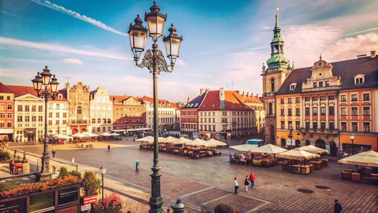 Bezpłatny plik Zdjęcie słoneczny dzień na placu europejskiego miasta z historycznymi budynkami, światłami ulicznymi i brukowanymi kamieniami