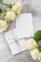 Bezpłatne zdjęcie Ślubne karty z różami na drewnianym tle