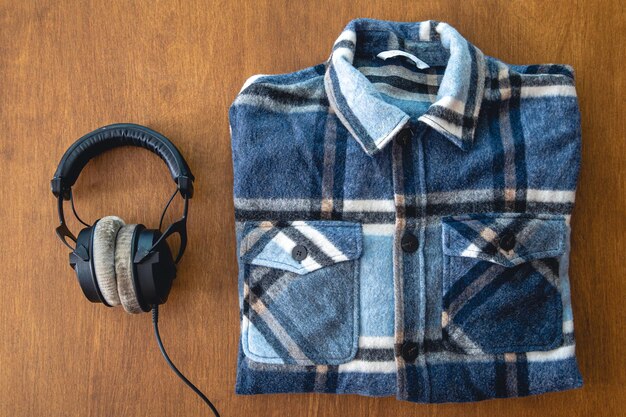 Słuchawki i złożona koszula w kratę na drewnianym tle