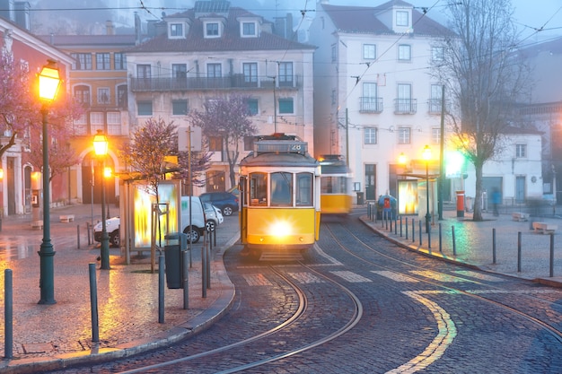 Słynny vintage żółty tramwaj 28 na ulicy alfama, najstarsza dzielnica starego miasta, w mglisty poranek, lizbona, portugalia