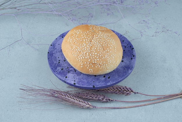 Bezpłatne zdjęcie smaczna bułka burger z sezamem na niebieskim talerzu