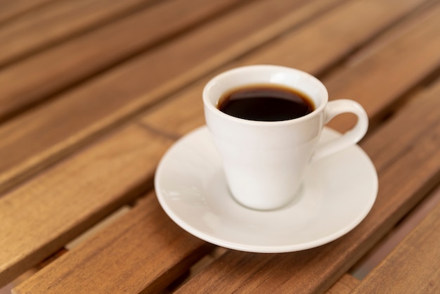 Smaczna filiżanka czarnej kawy na drewnianym stole