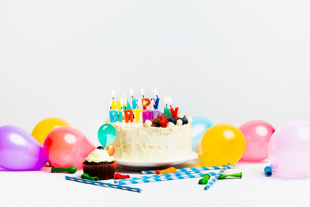 Smaczne ciasto z jagodami i szczęśliwy tytuł urodziny w pobliżu kolorowych balonów