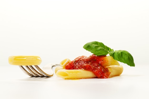 Smaczne kolorowe apetyczny gotowane spaghetti włoski makaron z sosem pomidorowym bolognese i świeża bazylia na rozwidleniu. Kreatywne służenie, zbliżenie.
