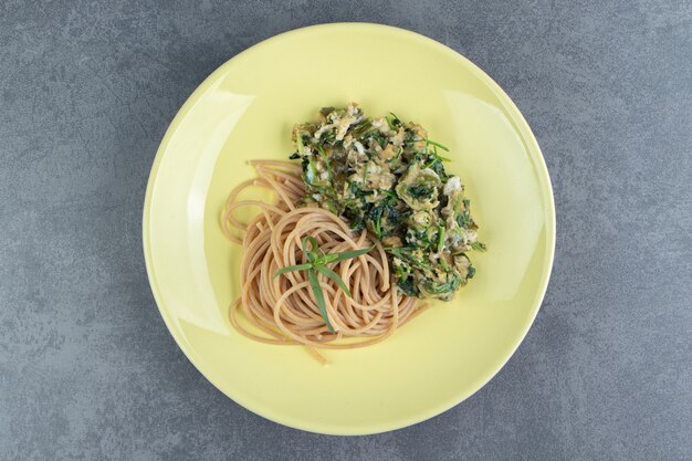 Smaczny omlet z zieleniną i spaghetti na żółtym talerzu.