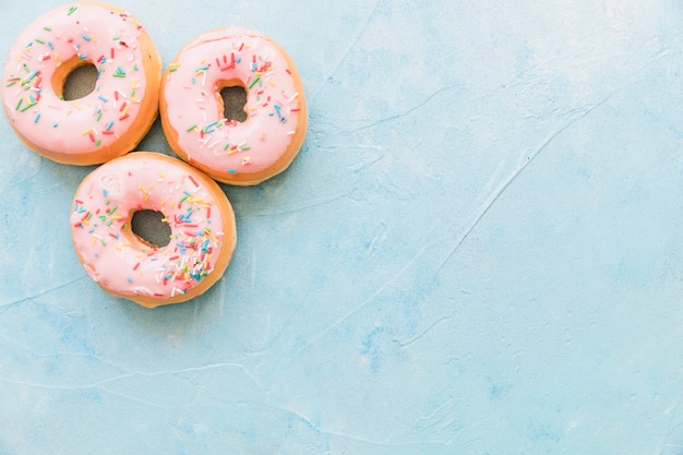 Smakowici różowi donuts dekorujący z kropią na błękitnym tle