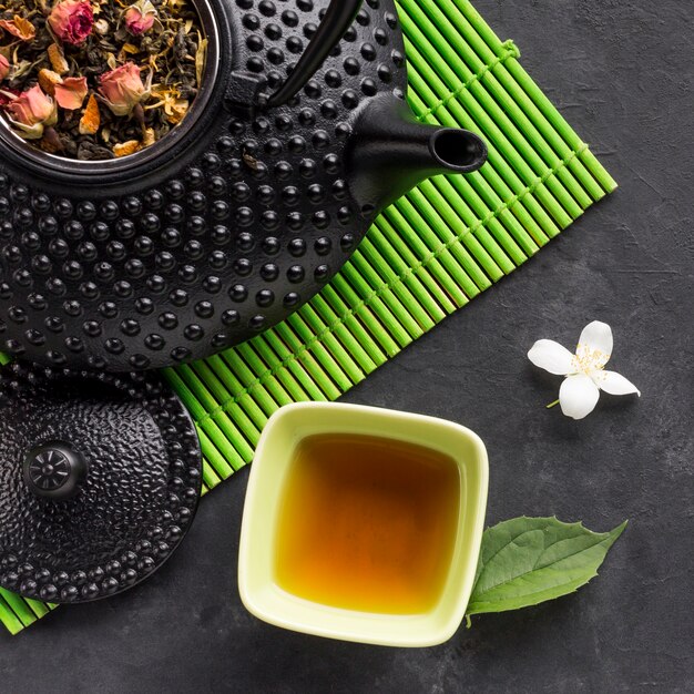 Smakowita ziołowa herbata i suchy herbaciany ziele z białym jaśminowym kwiatem na czarnym tle
