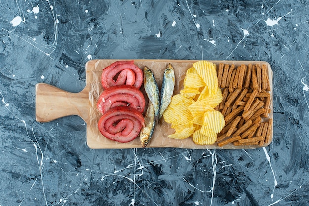 Bezpłatne zdjęcie smalec wieprzowy, ryba, frytki i bułka tarta na desce do krojenia, na niebieskim stole.