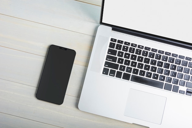 Smartfon leżący płasko obok laptopa