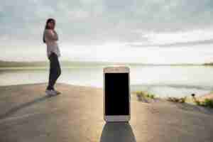 Bezpłatne zdjęcie smartphone przed kobietą opowiada na telefon komórkowy pozyci blisko jeziora