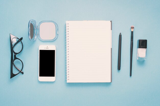 Smartphone z notatnikiem i kosmetykami na stole