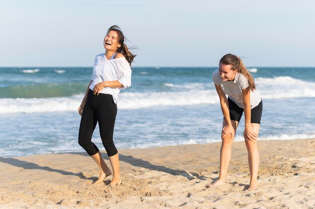 Śmiejąc się kobiety na plaży podczas joggingu