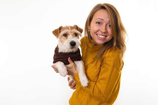 Śmiejąca się dziewczyna w żółtej kurtce trzyma w ramionach psa. izoluj na białym tle