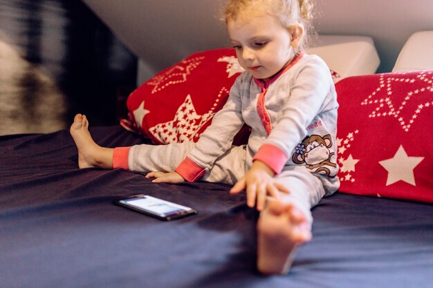 Bezpłatne zdjęcie Śmieszna dziewczyna ogląda wideo na łóżku