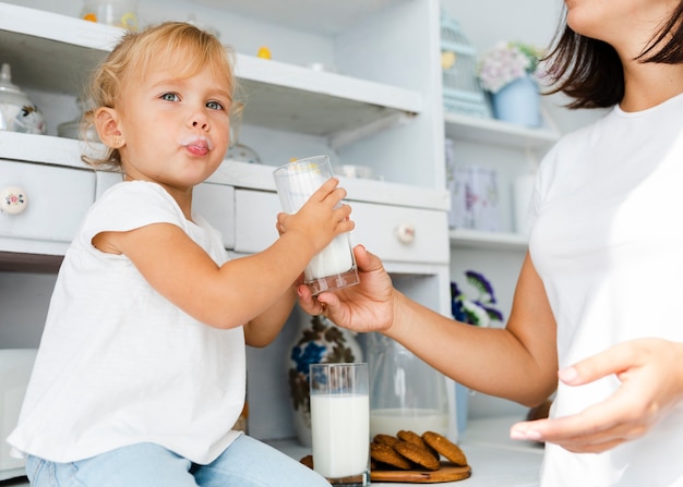 Śmieszna mała dziewczynka trzyma szkło mleko